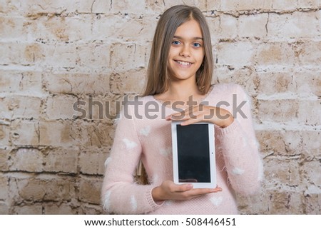picture of beautiful pre-teen girl with tablet pc. girl and tablet. Beautiful girl with long hair holds  tablet in the hands. Girl with tablet on beige background