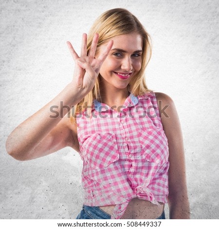 Blonde girl counting four on textured background