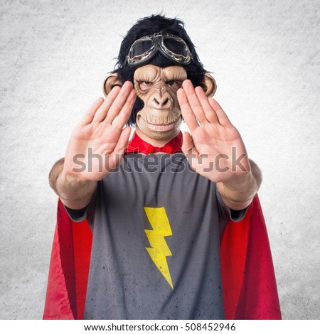 Superhero monkey man making stop sign on textured background