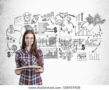 Smiling nerdy girl with a book is standing near concrete wall with black startup icons. Concept of startup foundation