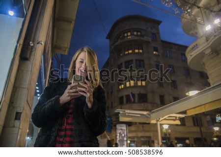Female using her mobile phone, city skyline night light background