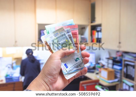 Hand holding Euro banknotes money with blur background of people working in a busy office. Cash on hand. economy concept, allocation of money. Business Man Displaying Cash. EUR Payment methods