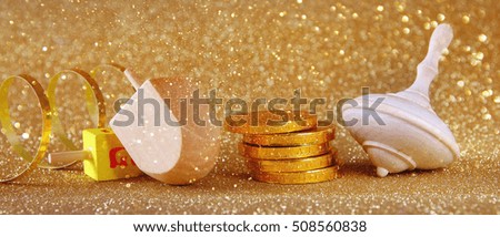Image of jewish holiday Hanukkah with wooden dreidel (spinning top) and chocolate coins on the glitter background. Wide format