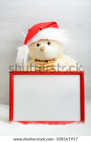 Teddy bear in santa hat next to the picture in the frame