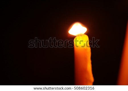 One candle burning brightly in the dark.