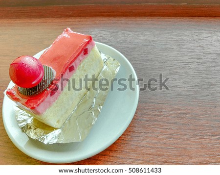 Close up picture of strawberry and yogurt cake white plate with brown wood table with morning lighting.