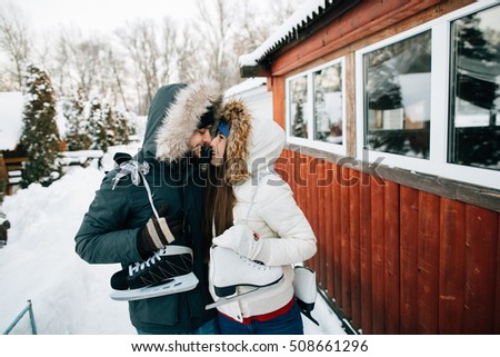 Winter. Couple in warm winter clothes with skates goes to the the ice rink.