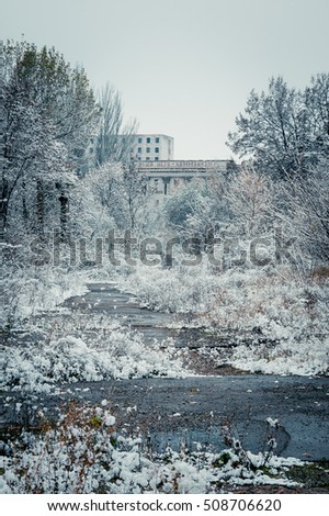 An old, abandoned building with the inscription "Our goal - communism." Overgrown structure of the Soviet Union. First day of winter. Snow on the trees. Toned photo of an old style.