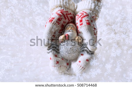 Christmas toy Santa Claus in the hands dressed in gloves on a white background