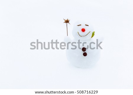 Portrait of very small, nice, smiling snowman in winter on the white snow background. Positive mood.