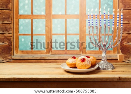 Hanukkah holiday sufganiyot with menorah on wooden table over window background