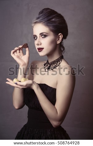 Portrait of young woman in witch halloween costume with candy smile over grey background