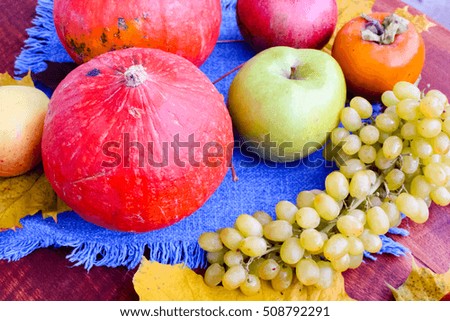 Autumn fruits still life among leaves on wooden table(nuts, apples, pumpkin)