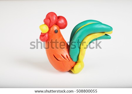 Plasticine figure: cock. Selective focus. On white background