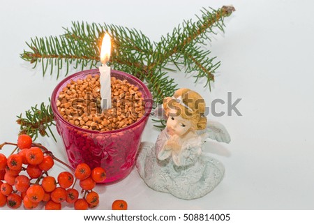 Fur-tree branch and candle on a white background. Figurine of an angel. Christmas mood