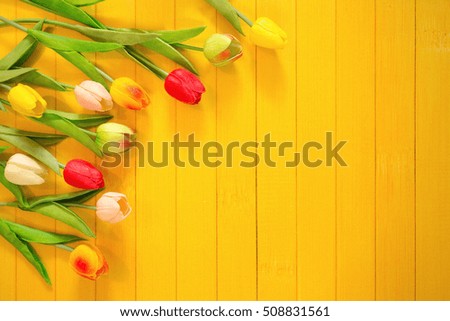 Tulips flowers on yellow wooden background. High top view.