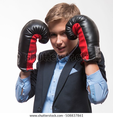 Emotional blond boy teenager in a suit with boxing gloves in hands on a white background