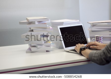 The man working with laptop on the table surrounded with stacked books.