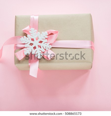 Christmas gift box for girl with pink ribbon and snowflakes on pink. Square image. 