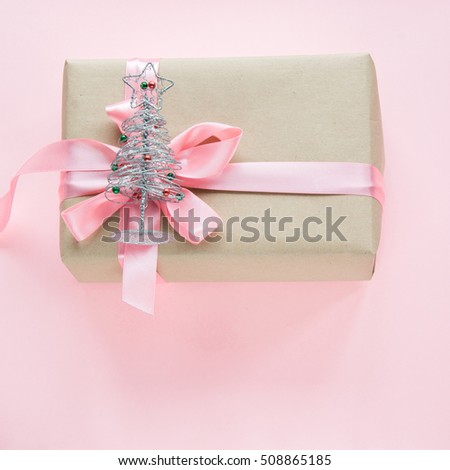 Christmas gift box for girl with pink ribbon and toy tree on pink. Square image.