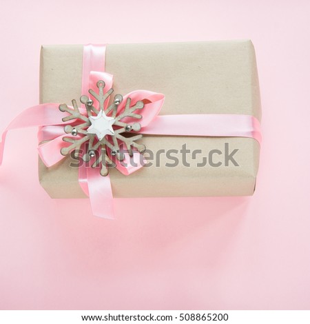 Christmas gift box for girl with pink ribbon and snowflakes on pink. Square image.