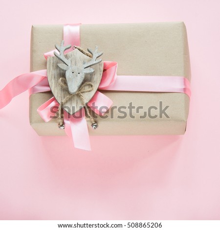 Christmas gift box for girl with pink ribbon and reindeer on pink. Square image.