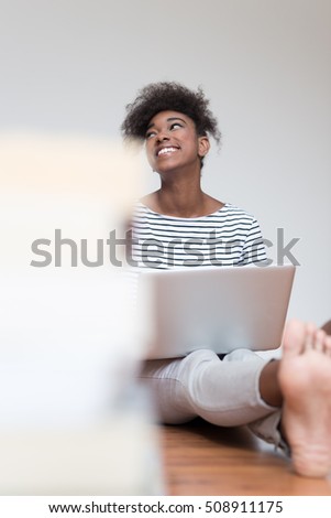 Good-looking African student girl with Afro hairstyle using laptop for doing research, preparing for lesson, surfing wi-fi in school, with enthusiastic look