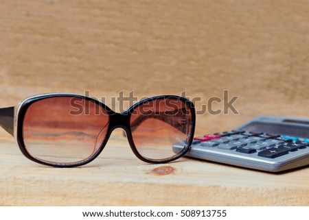 glasses with calculator on wooden background