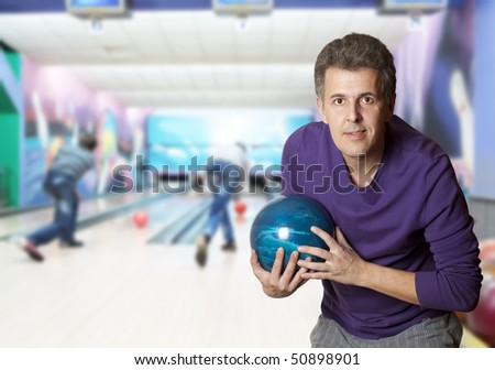 Adult man holding a bowling ball in a bowling alley
