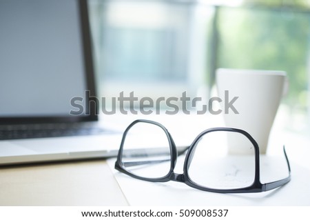 eyeglasses with blur laptop and cup of coffee