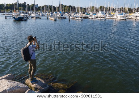 Photographer taking photo of boats at harbor.
