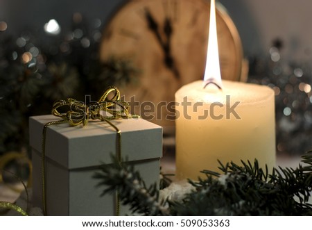 Christmas and New Year`s vintage clock showing five to midnight. Festive evening candle, white gift box gold bow, Christmas tree fir branches covered with snow. Concept for congratulations and party.