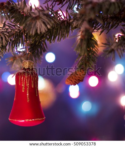 Christmas and New Year`s bokeh image. Red bell toy decorations on tree, fir cones and tree branches.  Greeting card Background concept with holiday tinsel with copyspace place for text or logo.