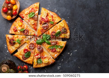 Homemade pizza with tomatoes, mozzarella and basil. Top view with copy space on dark stone table Royalty-Free Stock Photo #509060275