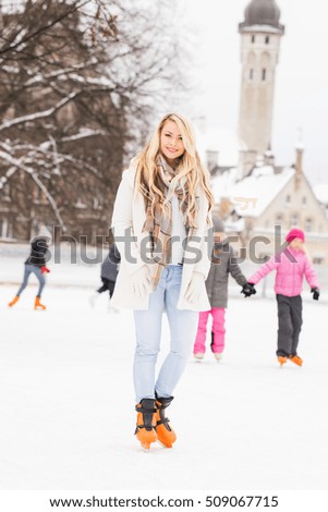 Young and pretty girl skating on outdoor open air ice-rink at winter.
