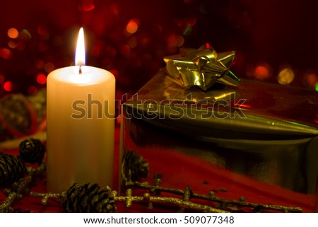Christmas and New Year`s  Festive evening candle, gold gift box gold bow, Christmas tree fir branches covered with snow.  Background concept with holiday tinsel, and copyspace place for text or logo.