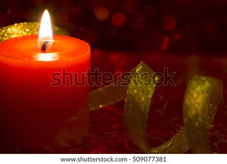 Christmas and New Year`s festive evening burning candle bokeh image.   Greeting card red Background concept with holiday tinsel with copyspace place for text or logo.