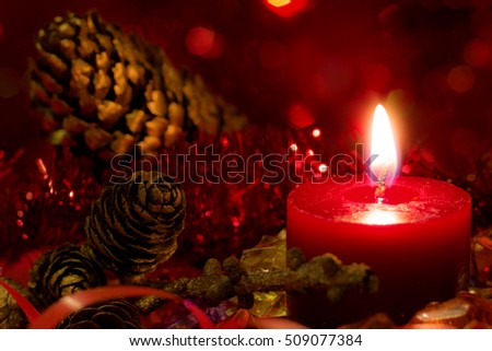 Christmas and New Year`s festive evening burning candle bokeh image. Greeting card dark Background concept with holiday tinsel, fir cones, tree banch and copyspace place for text or logo.