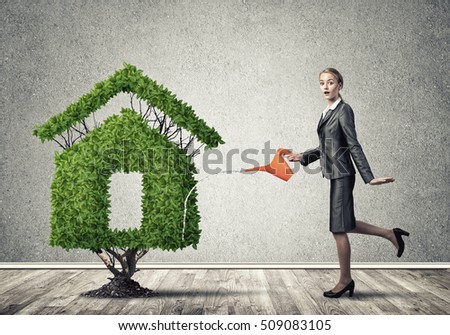Young attractive businesswoman watering plant in ground with can