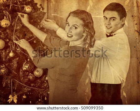 Old photo of loving couple preparing party near Christmas tree. Black and white retro picture.