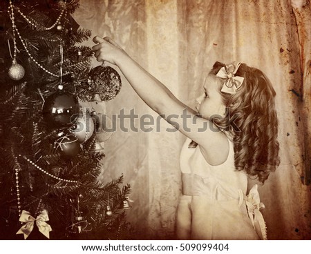 Retro old portrait of child girl decorate on Christmas tree. Black and white retro picture.