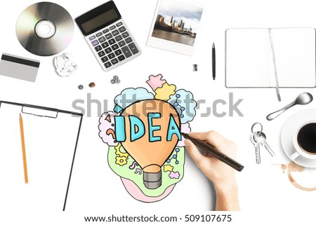 Close up of hand drawing creative lamp on white desktop with coffee cup, supplies, calculator and other items. Idea concept