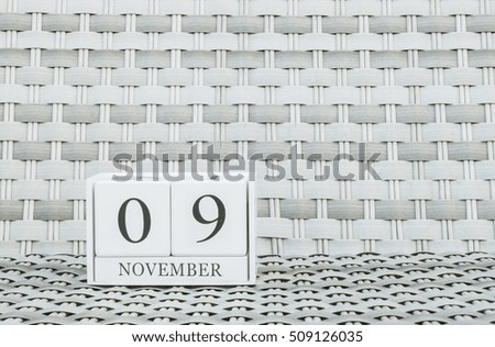 Closeup surface white wooden calendar with black 9 november word on blurred weave wood chair textured background with copy space , selective focus at the calendar