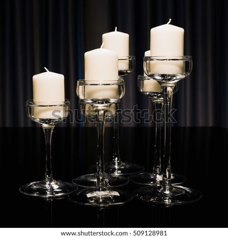 white candle in glass candlestick on a table mirror