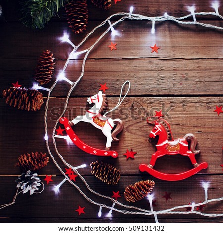 Festive Christmas composition on wooden background with vintage toy horse and Christmas lights