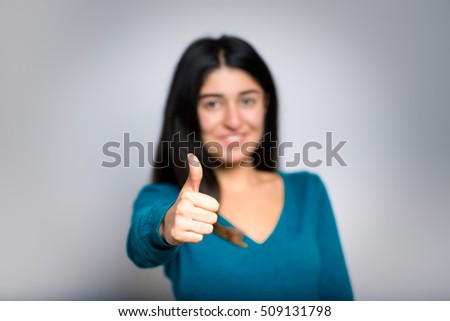 Brunette businesswoman showing thumbs up sign like a close-up isolated on a gray background