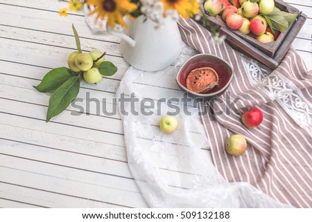 Yellow flowers in finally and apples on a light background