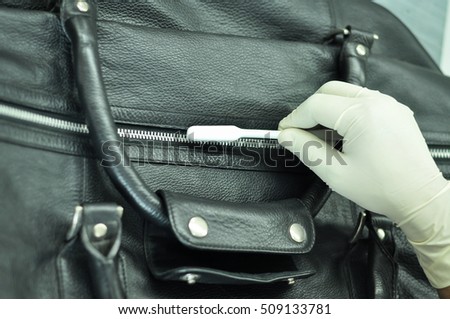 A leather factory worker cleaning a black leather bag with a cleaning brush. The hands of the worker covered with gloves and cleaning the bag with a small brush.  Royalty-Free Stock Photo #509133781