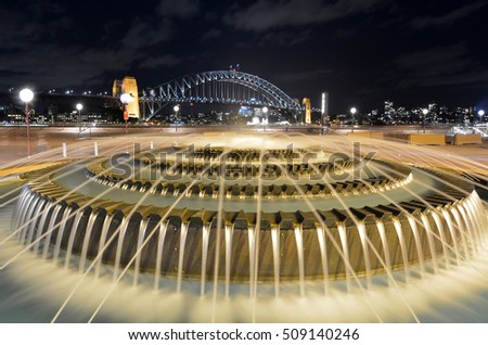 Water fountain in Sydney Waterfront Boardwalk against Sydney Harbour Bridge at night in Sydney New South Wales, Australia. No people. Copy spcae
