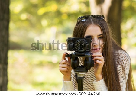 Beautiful woman with photo camera taking pictures in forest